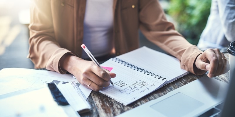 business women writing ideas in notebook